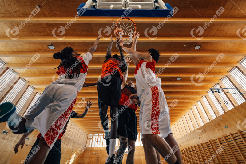 Bottom view of interracial basketball team at hoop in action on