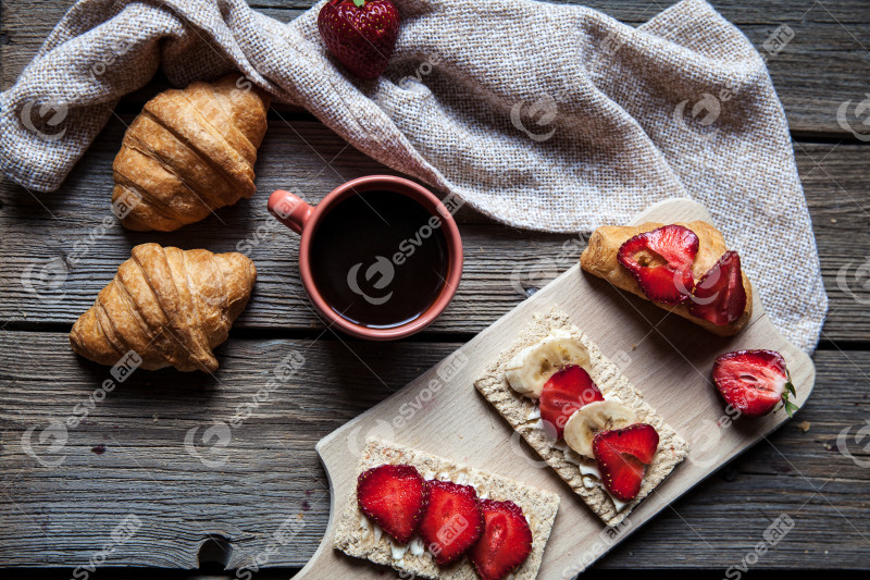 Delicious breakfast with a cup of coffee and fruit sandwiches, croissants. Strawberries, food, drink