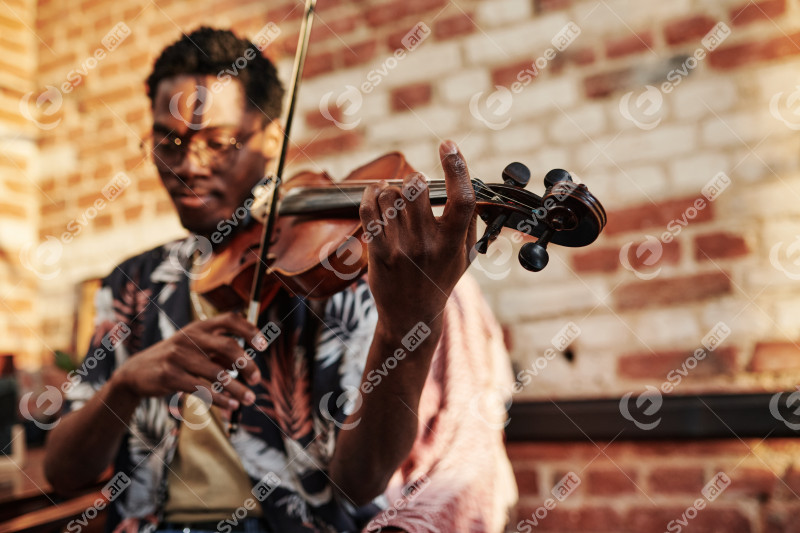 Hands of young black man holding fiddlestick and touching strings of violin