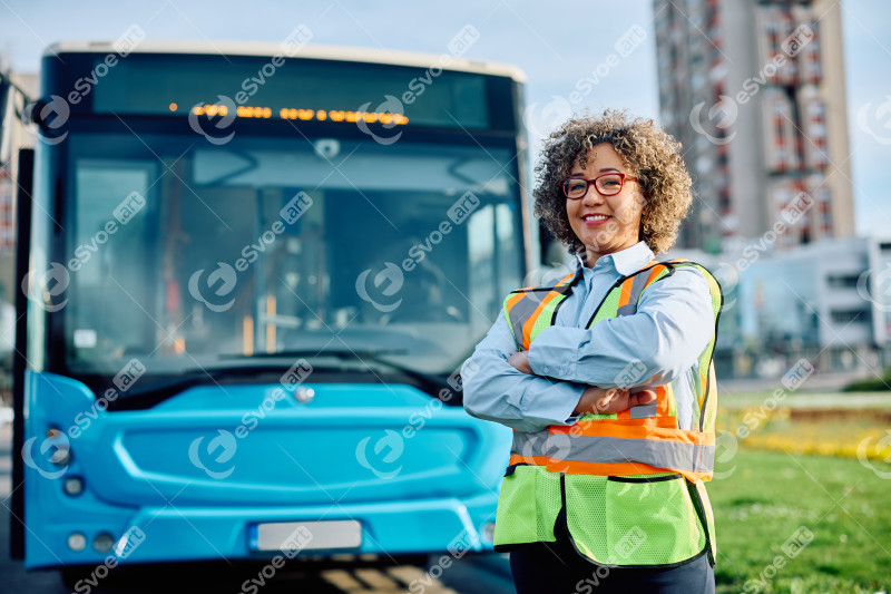 Happy bus driver standing with her arms crossed and looking at c