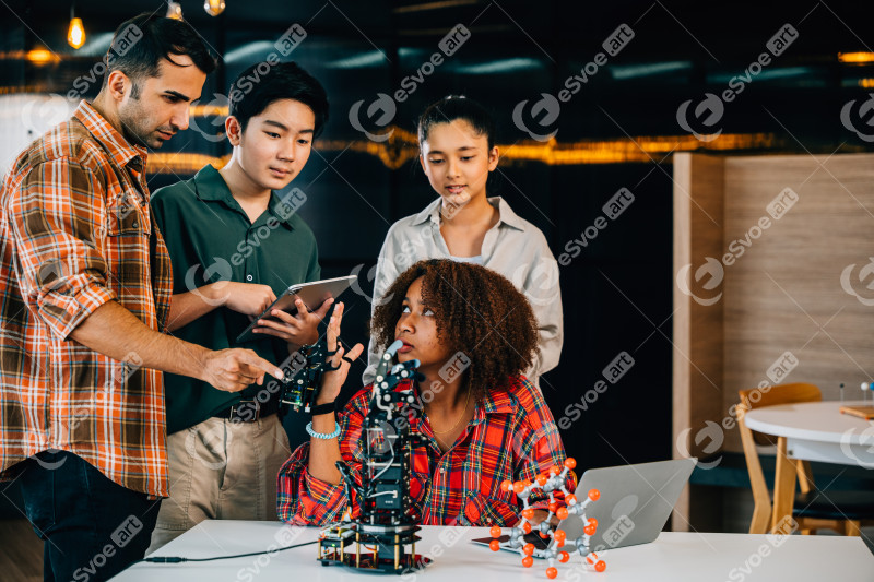 In a classroom at school students and teacher study and experiment on a robotic arm. Encouraging innovation teamwork and practical learning in education. Robot hand. Innovation and technology concept