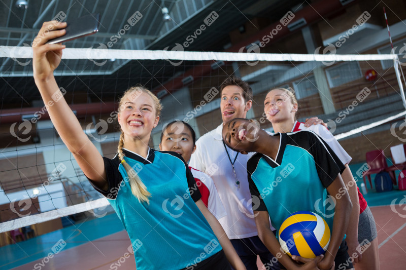 Male coach and volleyball players taking selfie