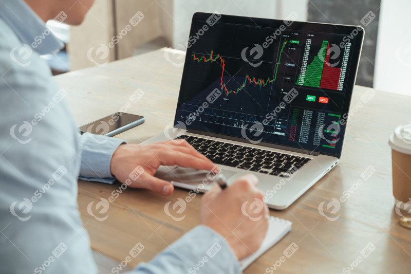 No face rare view of male hands scrolling diagram of crypto currency market on laptop, making notes