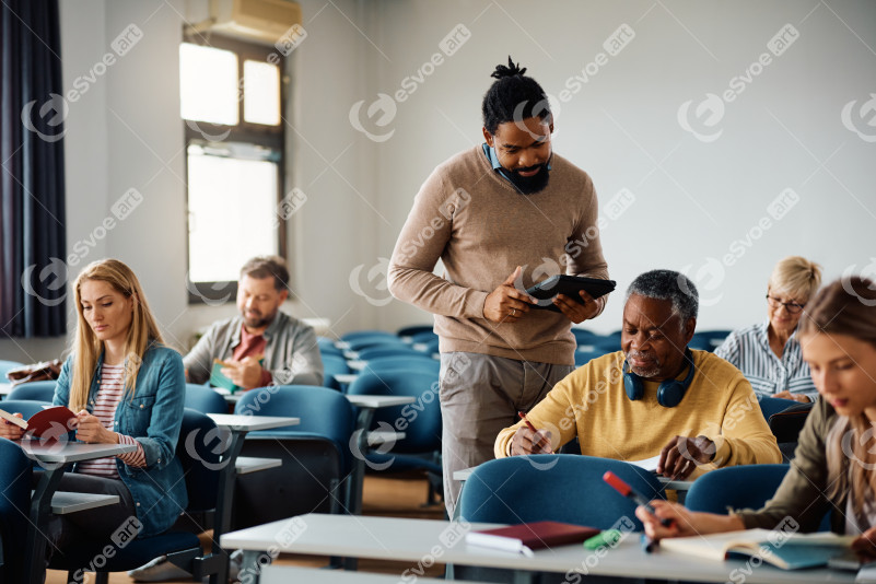 Smiling black adult education teacher with his student in a lect