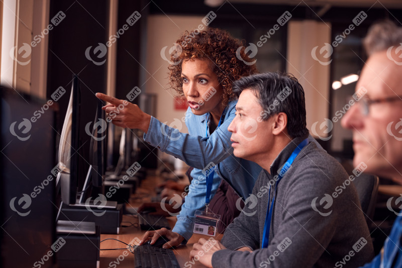 Teacher With Group Of Mature Adult Students In Class Working At