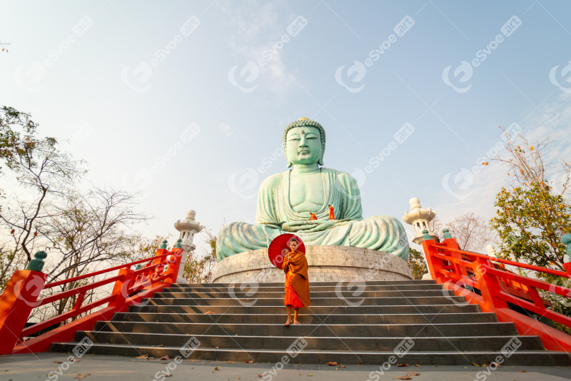 Wide shot of young asian monk hold red umbrella