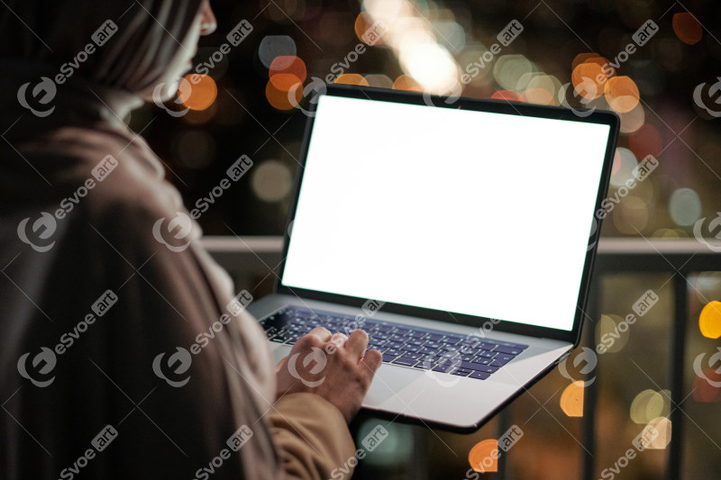 Young contemporary businesswoman with laptop standing on balcony